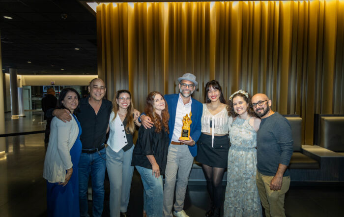 Grupo de personas posa junto a Ricardo Álvarez, actor, director, escritor y productor, quien sostiene un trofeo durante el Film Showcase de la Semana de Cine de Atlantic University en Caribbean Cinemas.