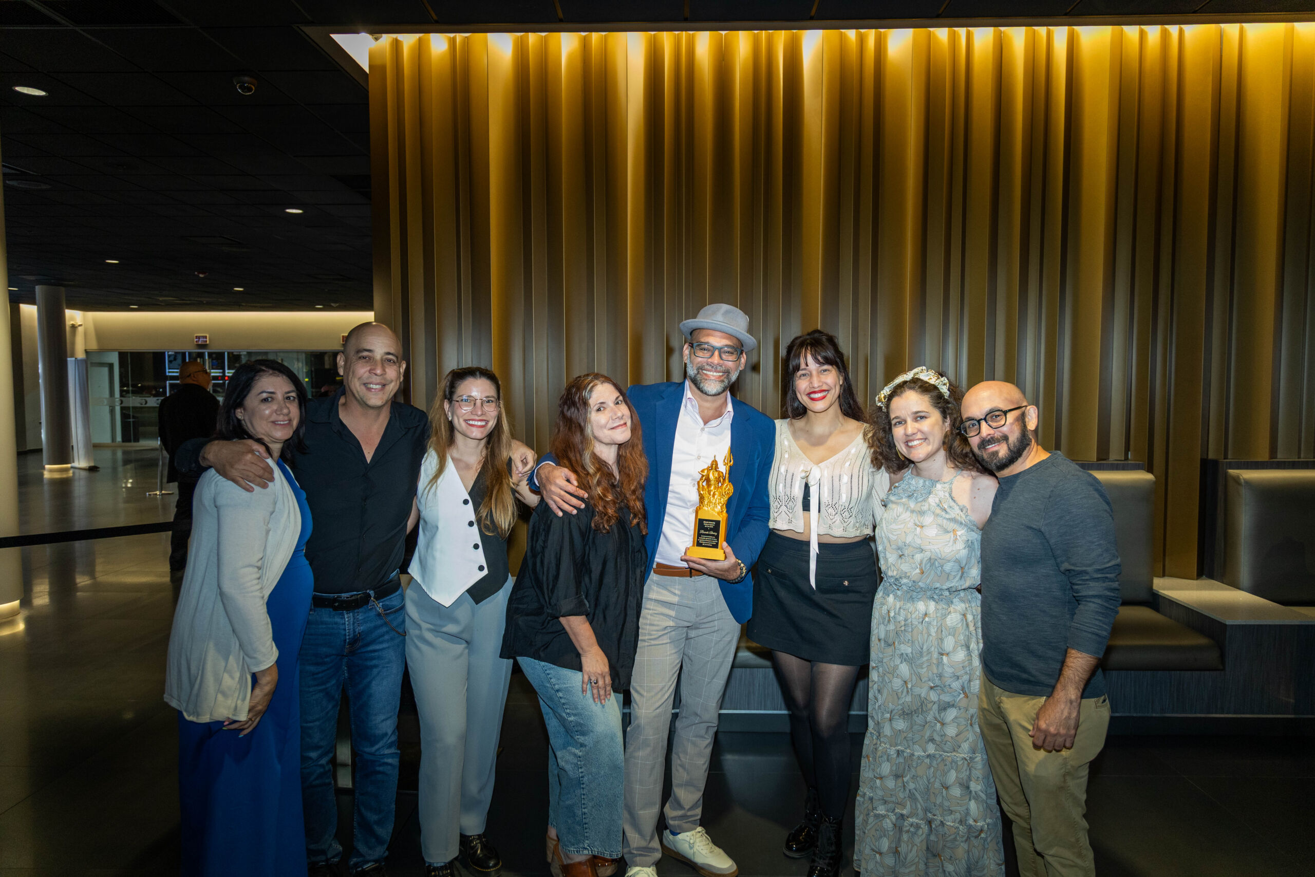 Grupo de personas posa junto a Ricardo Álvarez, actor, director, escritor y productor, quien sostiene un trofeo durante el Film Showcase de la Semana de Cine de Atlantic University en Caribbean Cinemas.